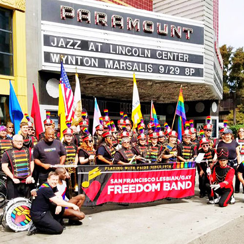 Marching band poses for a group picture in front of the Paramount Theatre in Oakland