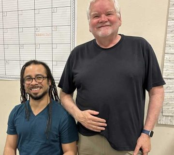Carlos McMillan Fuentes seated with Artistic Director Pete Nowlen standing beside him.