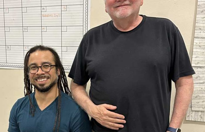 Carlos McMillan Fuentes seated with Artistic Director Pete Nowlen standing beside him.