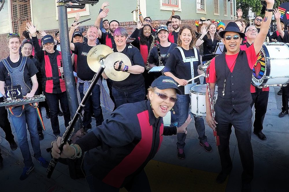 San Francisco Pride Band's Pep Band poses with drums, cymbals, and instruments in the Castro.